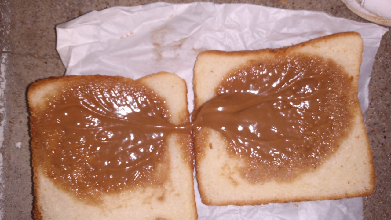 An open-faced sandwich with viscous-looking peanut butter. 