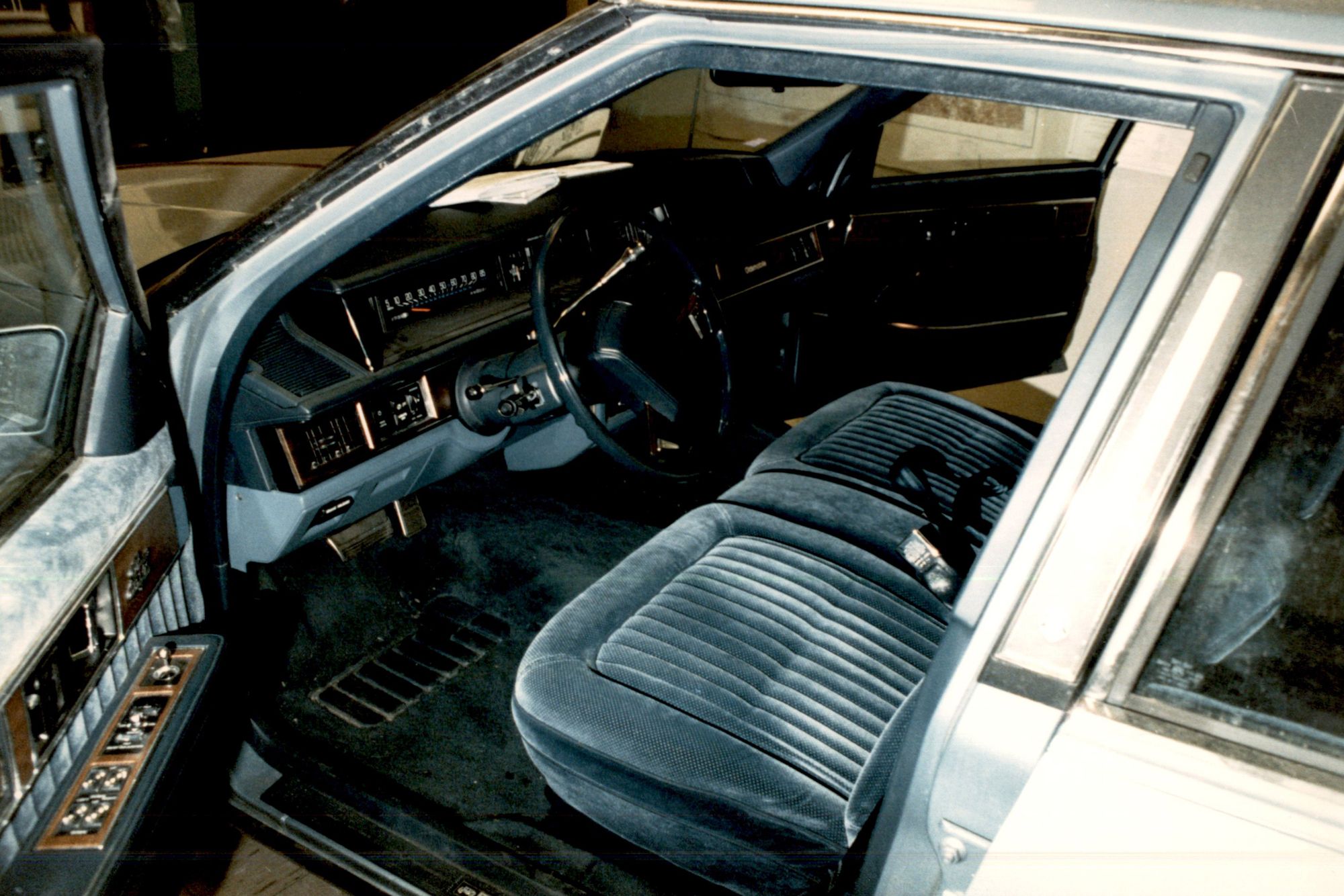 An Oldsmobile with gray-blue velvet seats has its driver’s side door open. 