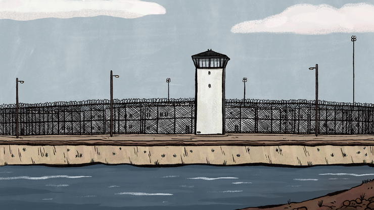 A scene outside the Corcoran prison complex with a razor-wire topped fence and white observation towers behind it. A water-filled canal runs alongside the facility.