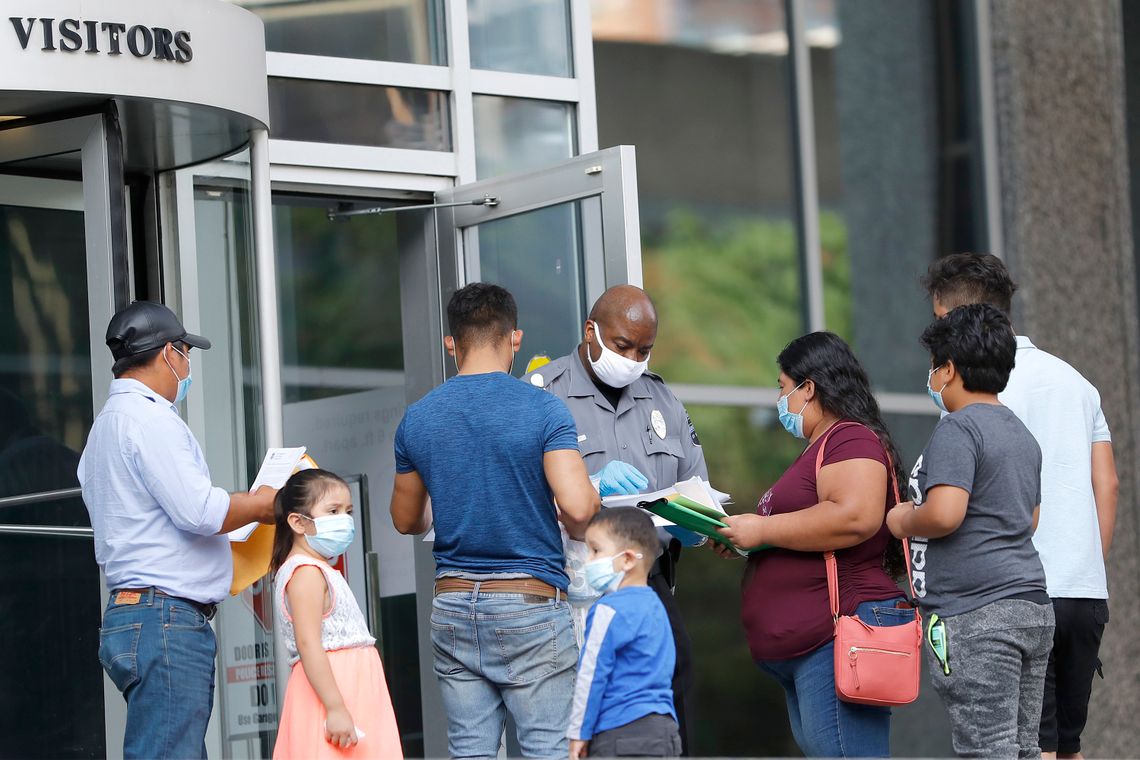 A security officer, center, meets with people outside the immigration court in a federal building in Baltimore to give them a form to come back at a later date because of the coronavirus pandemic, on Monday, July 13, 2020, in Baltimore, Md. 