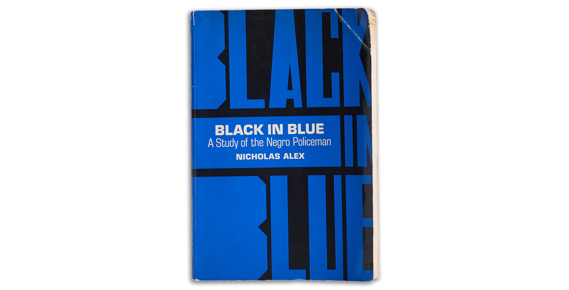 The cover of the book “Black in Blue: A Study of the Negro Policeman” by Nicholas Alex is visible, in bold type, with a black-and-blue color scheme. 