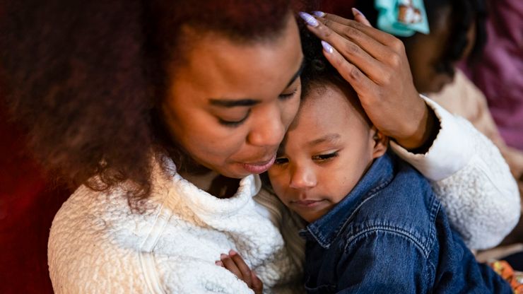 A photo shows a Black woman embracing her child. 