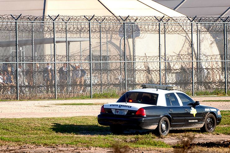 Prisoners stand at the western fence as law enforcement officials from a wide variety of agencies converge on the Willacy County Correctional Center in Raymondville, Texas on Friday, Feb. 20, 2015 in response to a prisoner uprising at the private immigration detention center. A statement from prison owner Management and Training Corp. said several inmates refused to participate in regular work duties early Friday. Inmates told center officials of their dissatisfaction with medical services. (AP Photo/Valley Morning Star, David Pike)