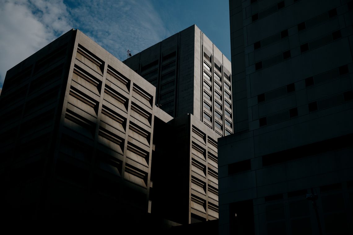 A view of the top of the Cuyahoga County Justice Complex, which includes the county jail.  The building is beige and has narrow horizontal windows, and is partly in shadow.