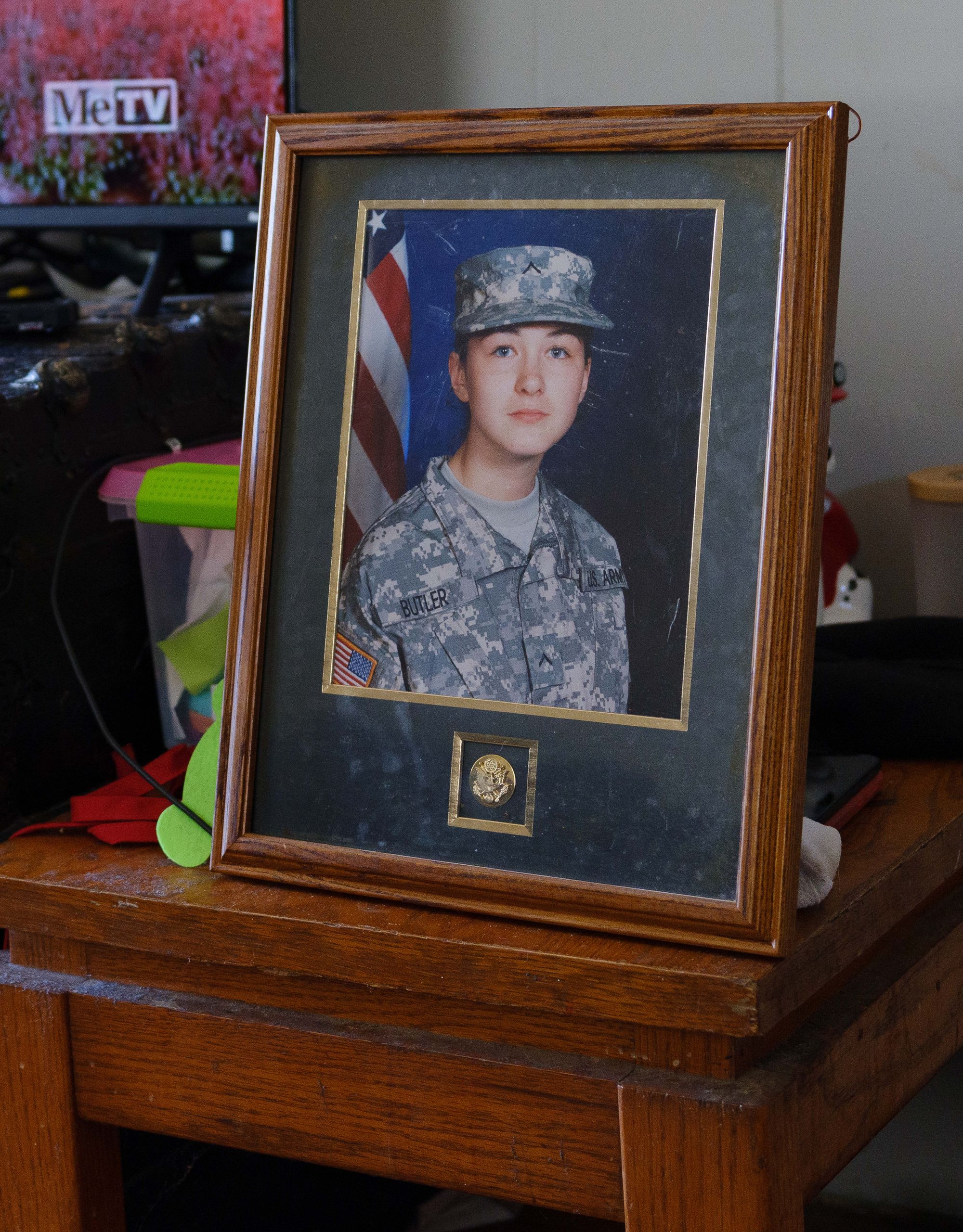 A photo of Quitney Armstead, a White woman in a military uniform, sits in a frame on a wooden table. 
