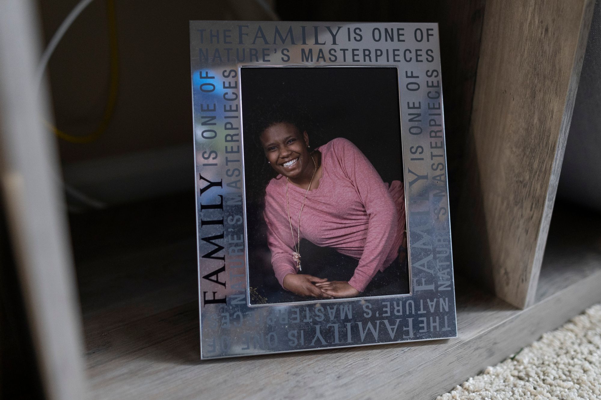 A silver picture frame with a photo of a smiling Black woman in a pink sweater.