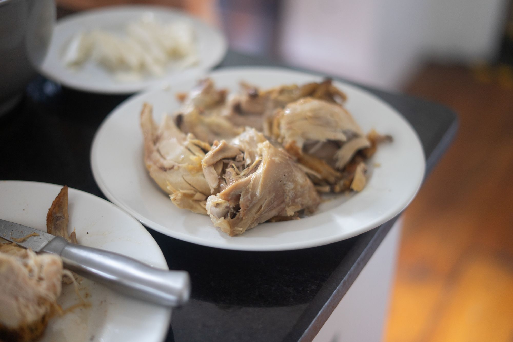 White plates of roasted chicken sit on a dark counter.
