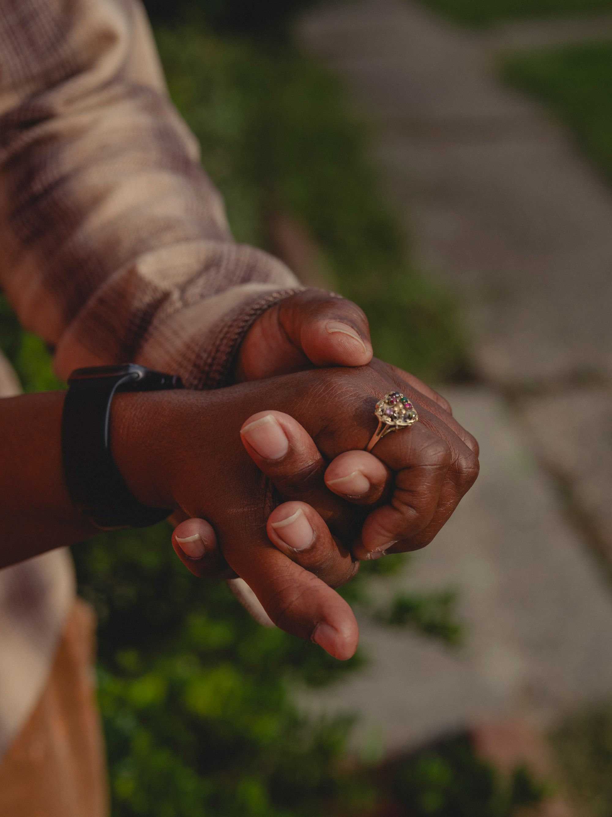 A closeup of Raymond holding Cassandra’s hand, with a ring on her index finger.