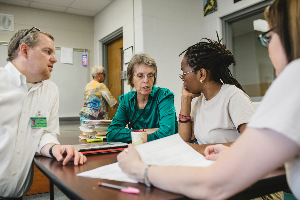 Andrew Falk, left, works with Kelsey Kauffman, center, Michelle Jones, center-right, and Natalie Medley, far right, in the housing policy class at the Indiana Women's Prison.