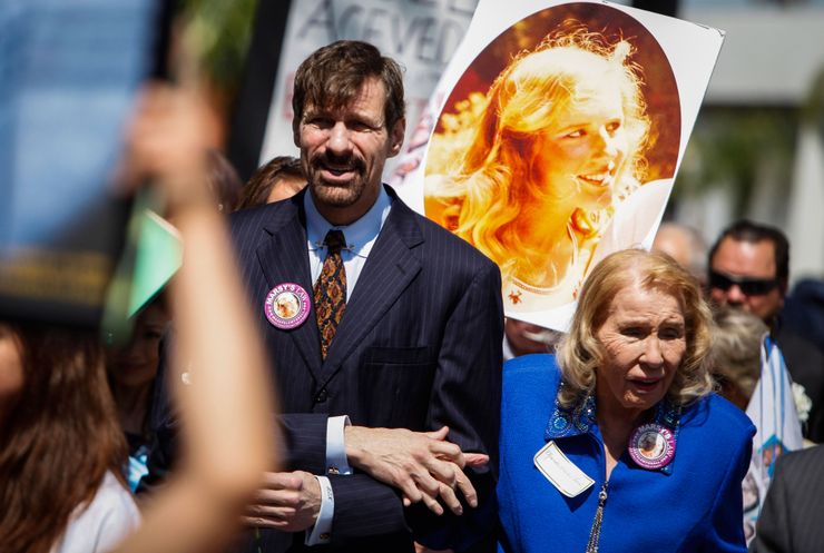 Henry T. Nicholas III, left, and his mother, Marcella Leach, with a photo of his sister, Marsy Nicholas, during the Orange County Victims’ Rights March and Rally in 2013.