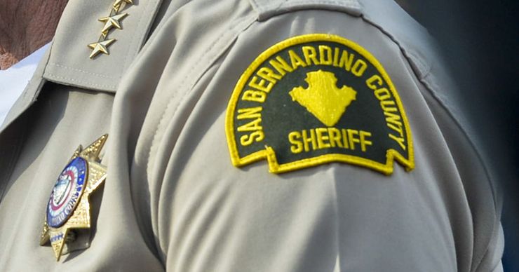 A close-up photo shows the shoulder of a deputy with a San Bernardino County sheriff patch. 