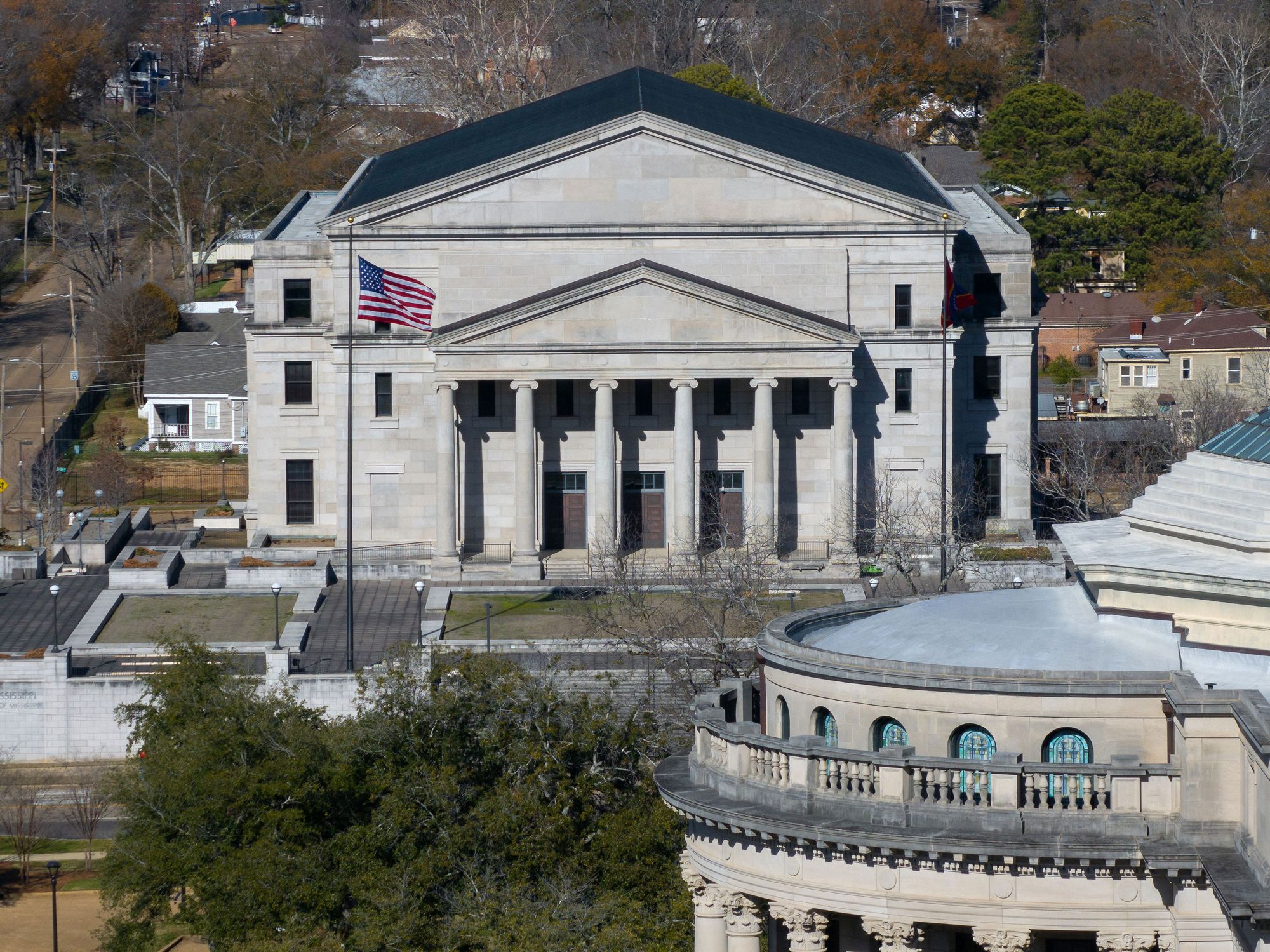 An aerial photograph of the Mississippi Supreme Court building, a beige, multi-story building with a pointed roof and columns. 