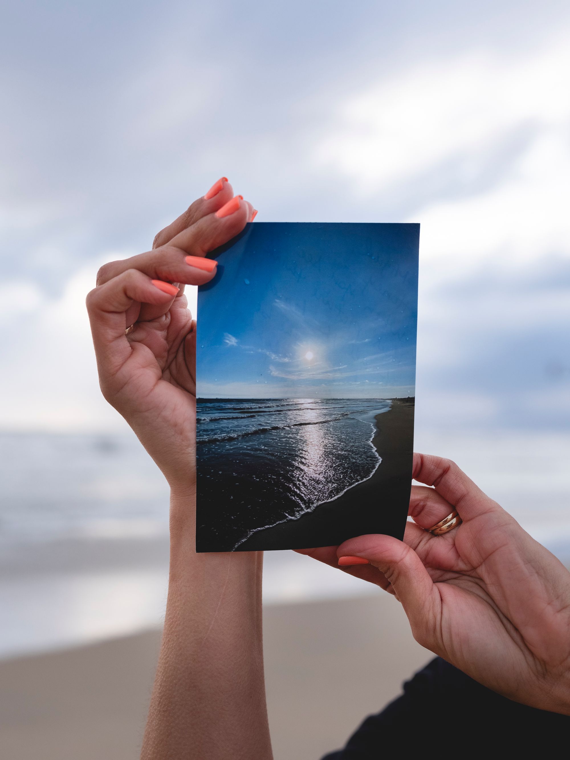 Silvia's hands are visible, holding up a photograph of the blue sky and ocean.