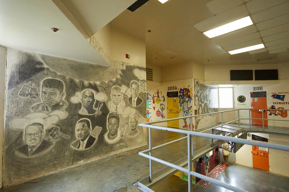 A view of part of the interior of the Turbeville Correctional Institution shows a wall on the left side of the photo with a black and white mural depicting people including former President Barack Obama, Nelson Mandela and Martin Luther King Jr. On the right side, there are prominent Black women drawn in a mural, including Rosa Parks and Maya Angelou. To the right of the photo you can see over the edge of the balcony down to the floor below.