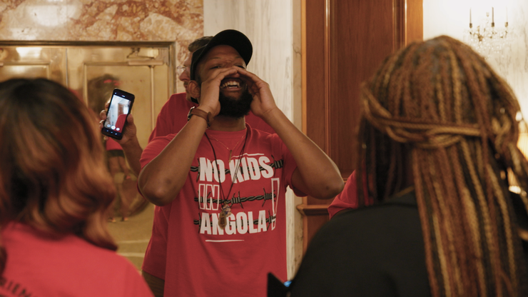 A Black man wearing a red T-shirt that reads “No kids in Angola” shouts during a protest at the Louisiana state Capitol against the state’s decision to house some youth at the adult prison Angola.