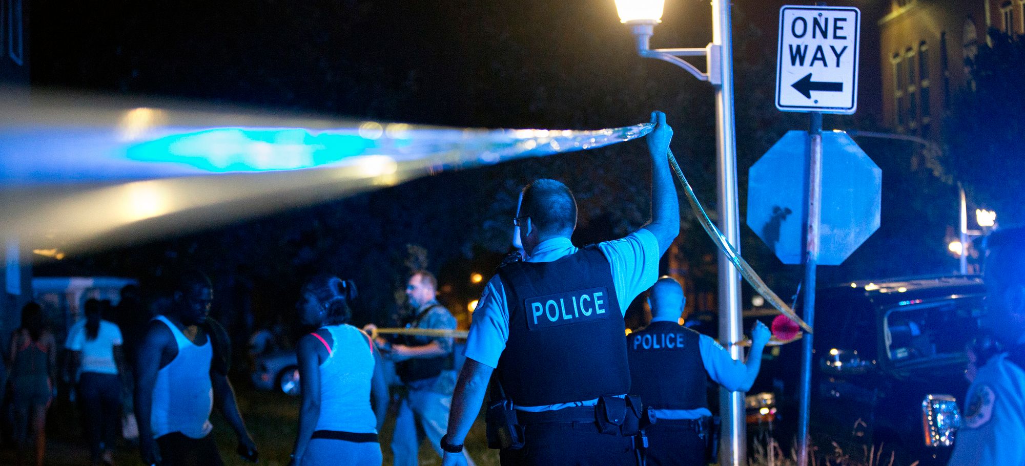 Members of the Chicago Police Department put up tape and clear the scene of a fatal shooting in June in the city's East Garfield Park neighborhood.