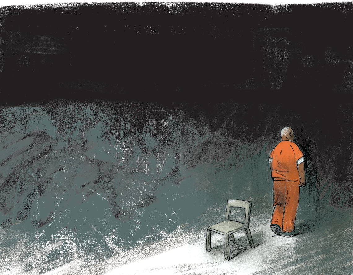 Belcher, in his orange prison uniform and visible from the back, is walking away from a chair to return to his cell. 