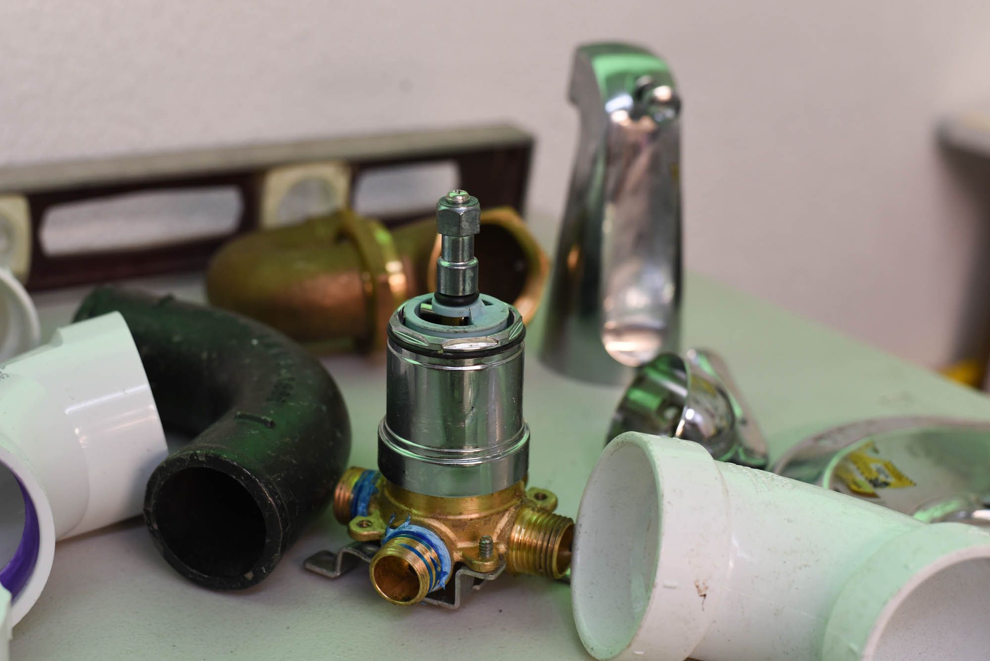 A selection of faucets, pipes, and drains are scattered on a countertop.