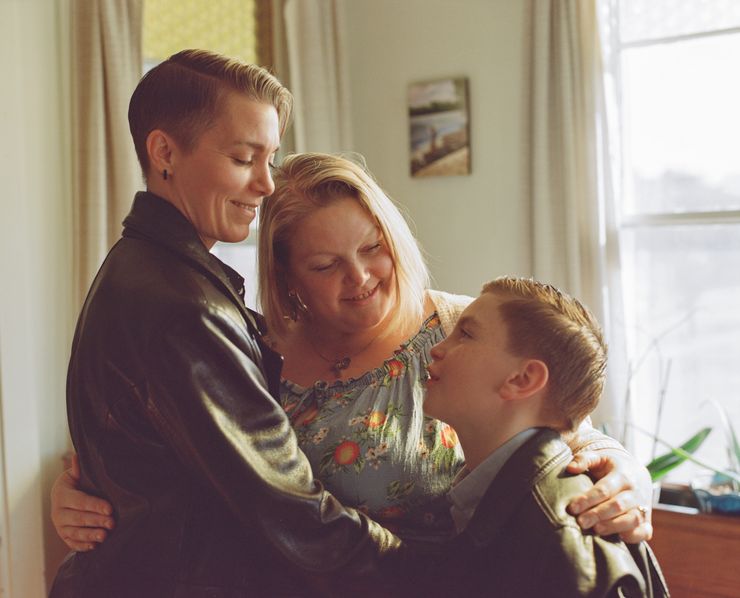 Jules Werkheiser, a White person wearing a leather jacket, with her wife, Samantha, a White woman wearing a blue floral dress, and their son, Julius.