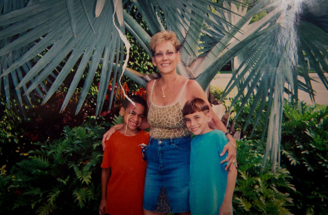 A family photo of a woman smiling with two young boys. 