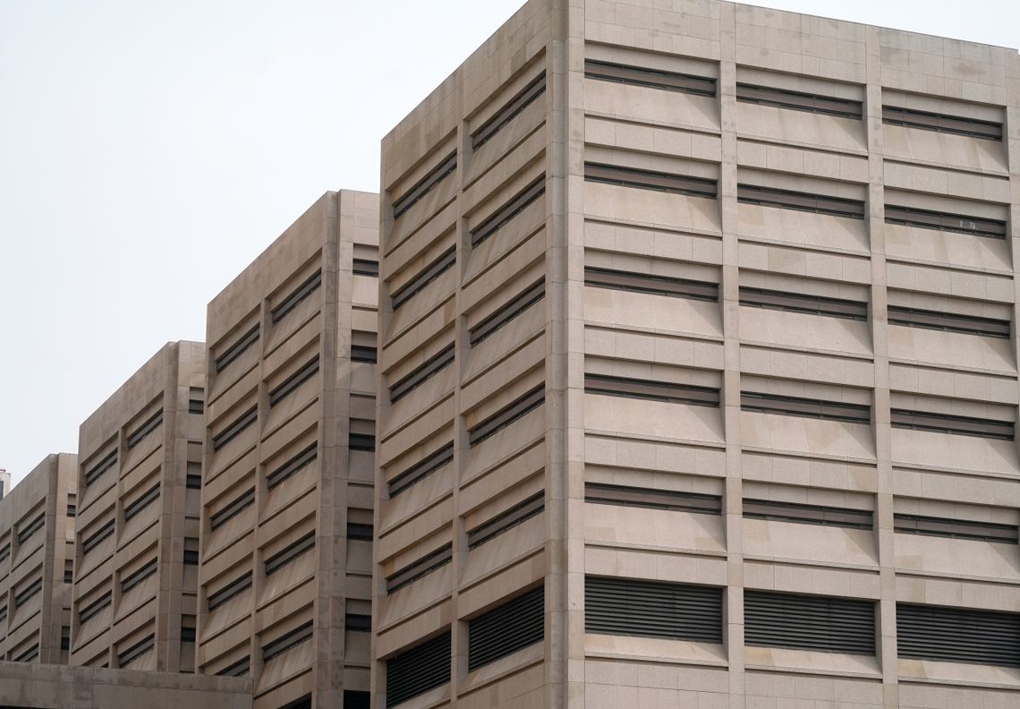 A photo of the Cuyahoga County Justice Center Complex, which includes the county jail. Four beige multistory buildings with narrow horizontal windows stand in a row against a pale sky.