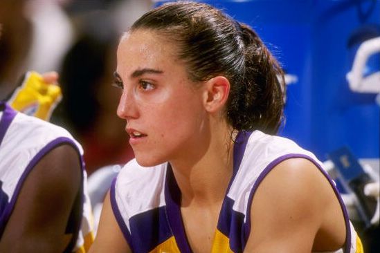 A woman with medium skin tone sitting in a basketball uniform. 