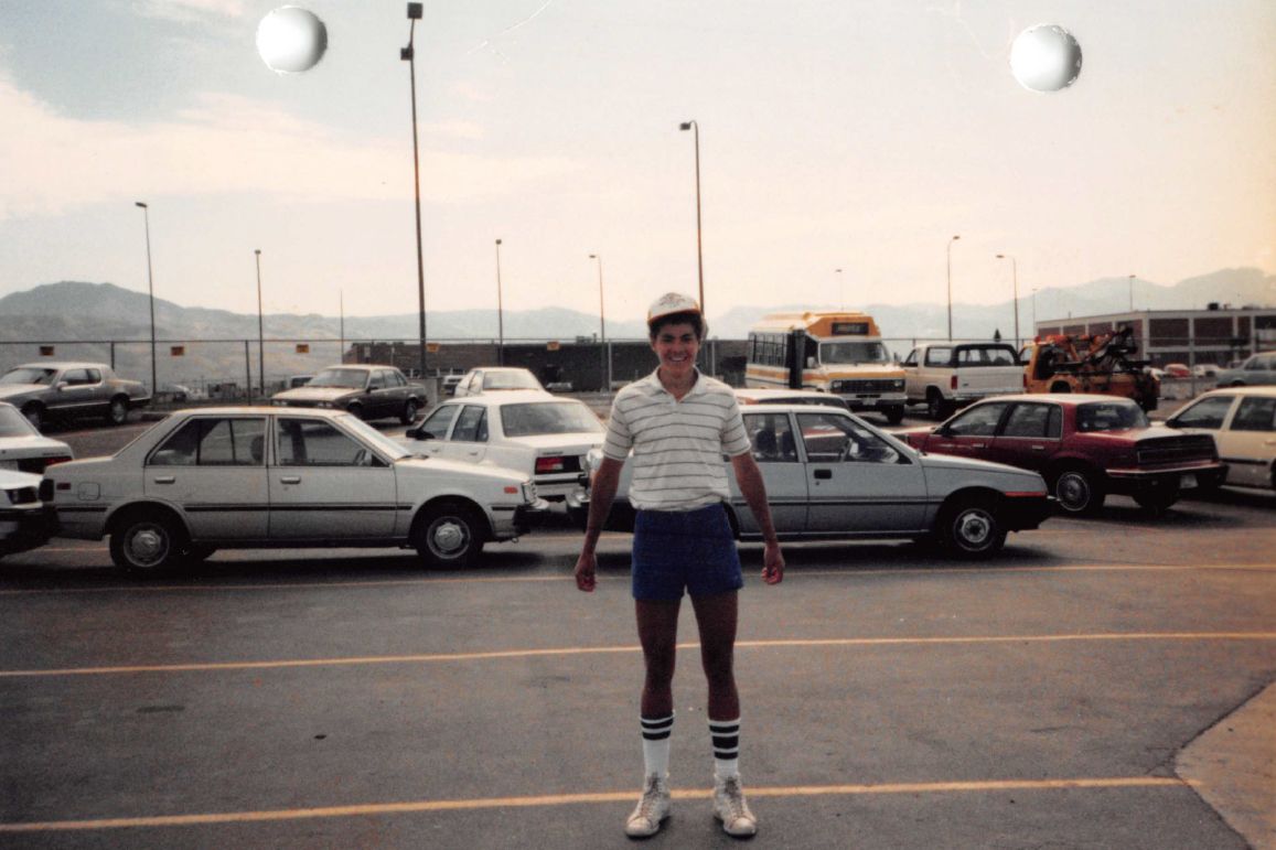 Jake Wideman, a multiracial teenage boy, standing in a parking lot full of cars. 