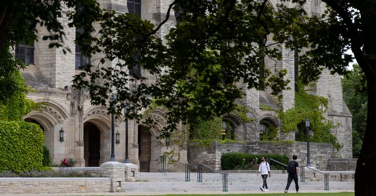 Two students walk past a university building. 