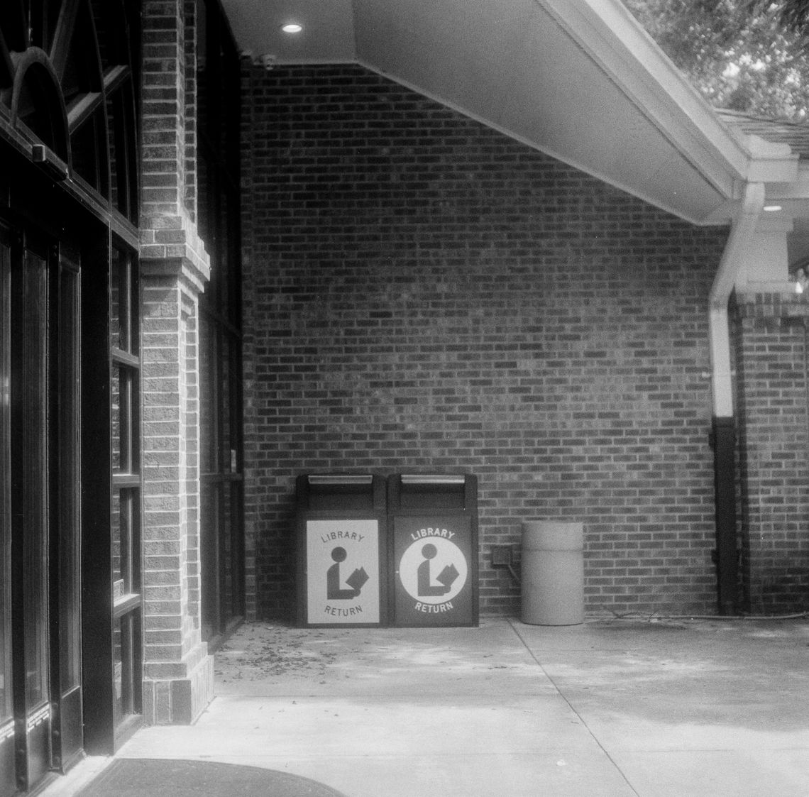 From left to right, black-and-white photos show a row of patterned chairs with wooden legs in a carpeted room, rows of bookshelves in a library, and two book drop boxes outside a library. 