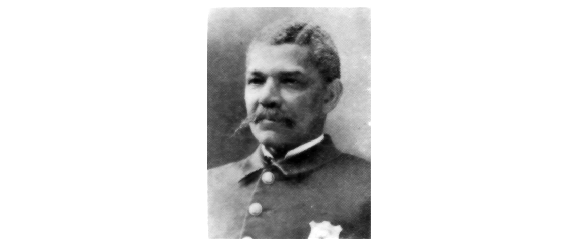 Black-and-white early photograph of William Manual Tucker, believed to be Cleveland’s first Black police officer. Tucker is wearing a uniform with a badge and has a thick mustache.