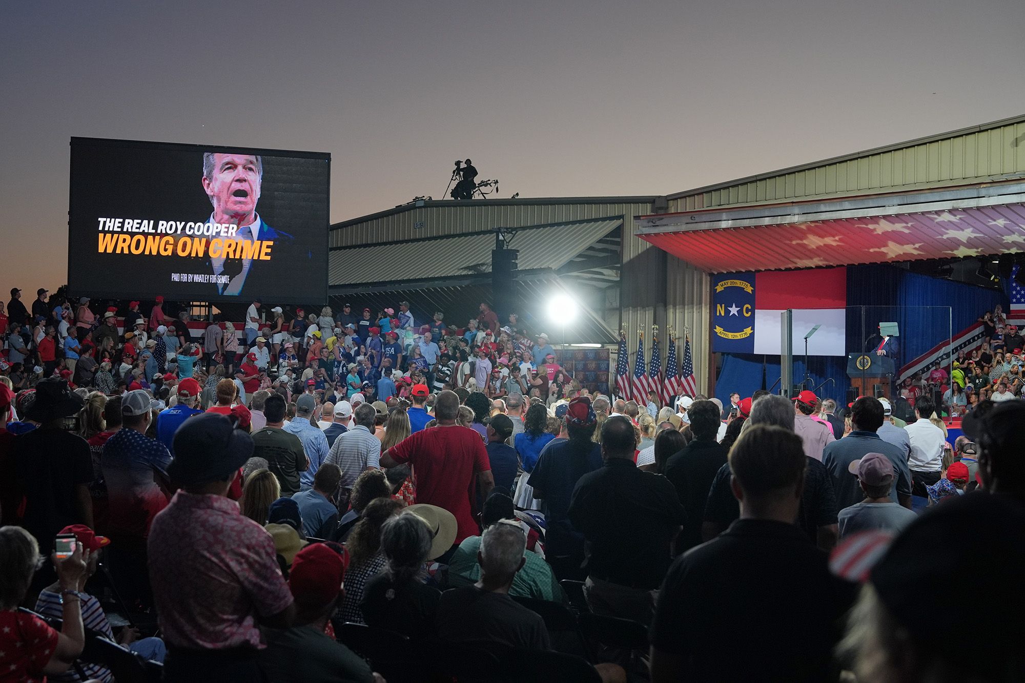 A photo shows hundreds of people standing at a campaign rally as they look at President Donald Trump standing at a podium. 
