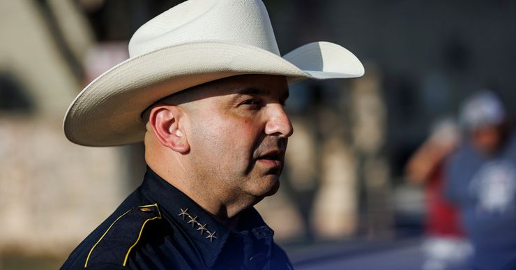 A photo of a man with medium-toned skin, wearing a cowboy hat and a navy blue sheriff's uniform.  