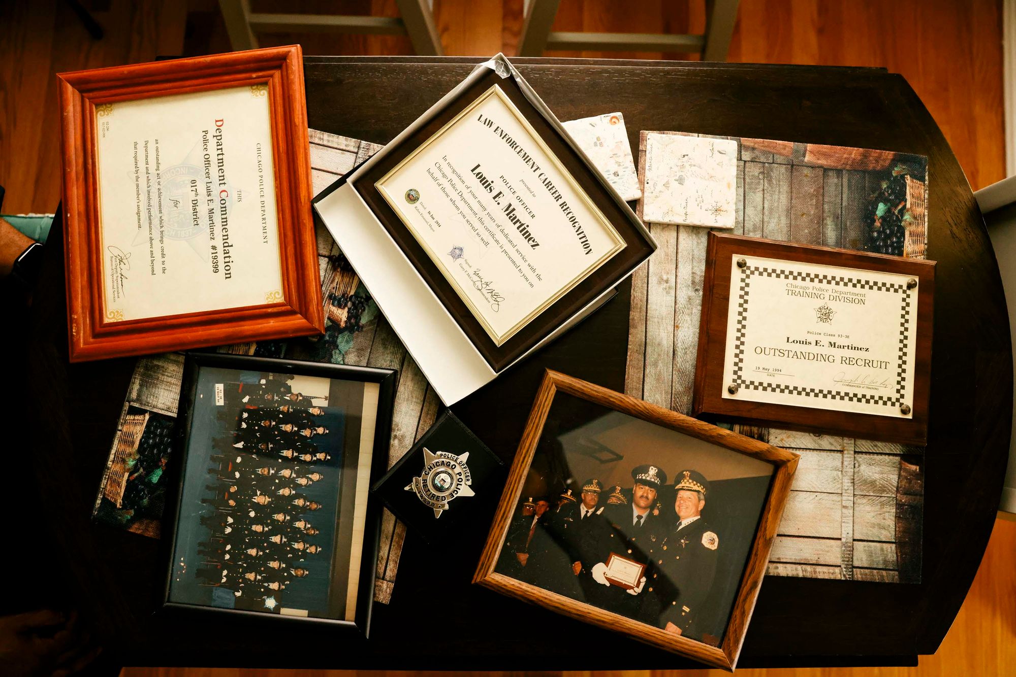 A photo shows a framed photo of a group of uniformed police officers; a framed commendation from the Chicago Police Department for Martinez; a framed career recognition signed by the superintendent; and a framed training award from the Chicago Police Department.