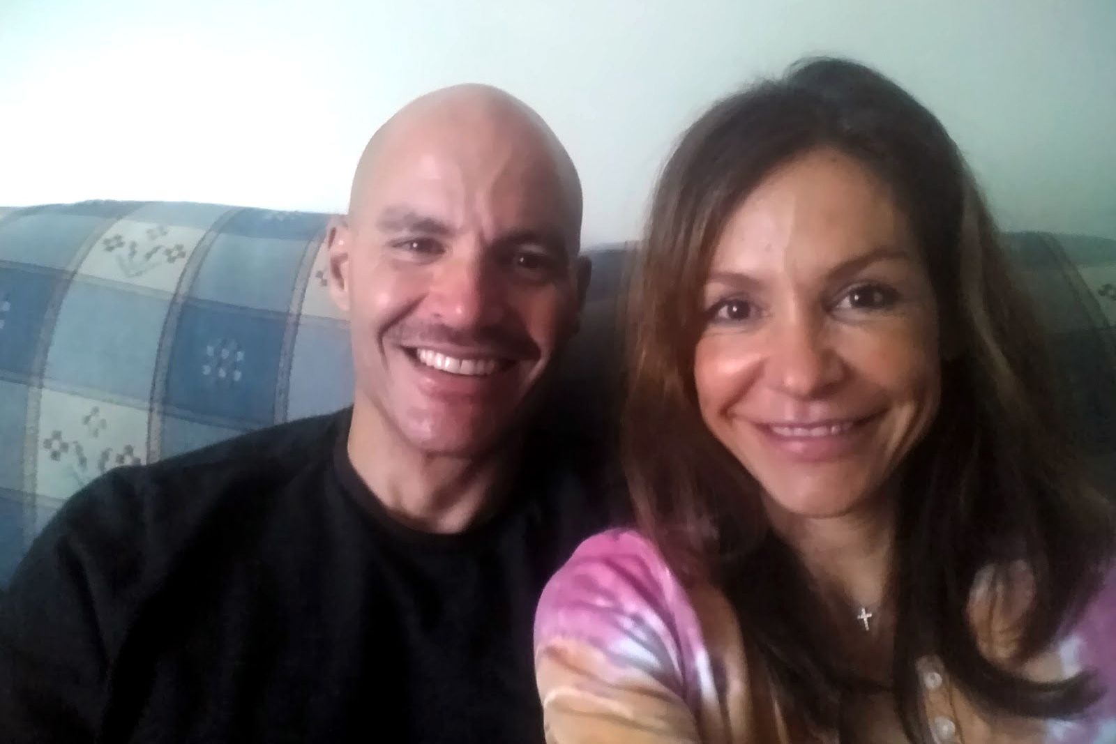 Jacob Wideman, a multiracial man, sits with his wife, Marta DeSoto, a Spanish woman, on a couch. 