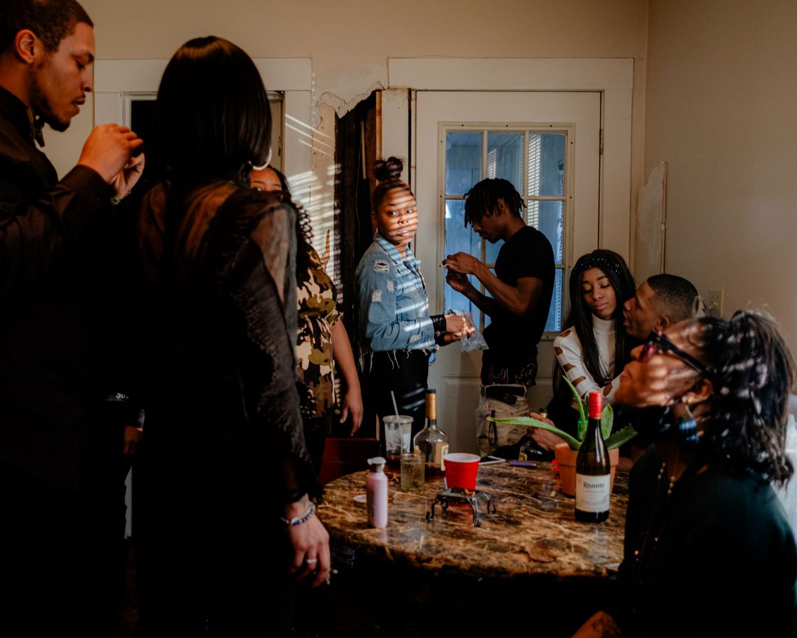 A photo of a group of Black friends and family members around a table inside a home. 