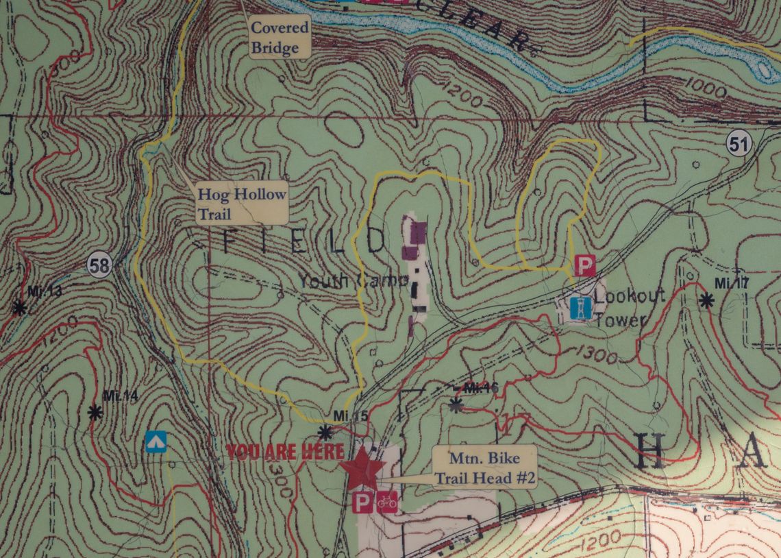 A photo of a shadow falling on a topographic map showing trails in a state forest and the location of a youth camp.