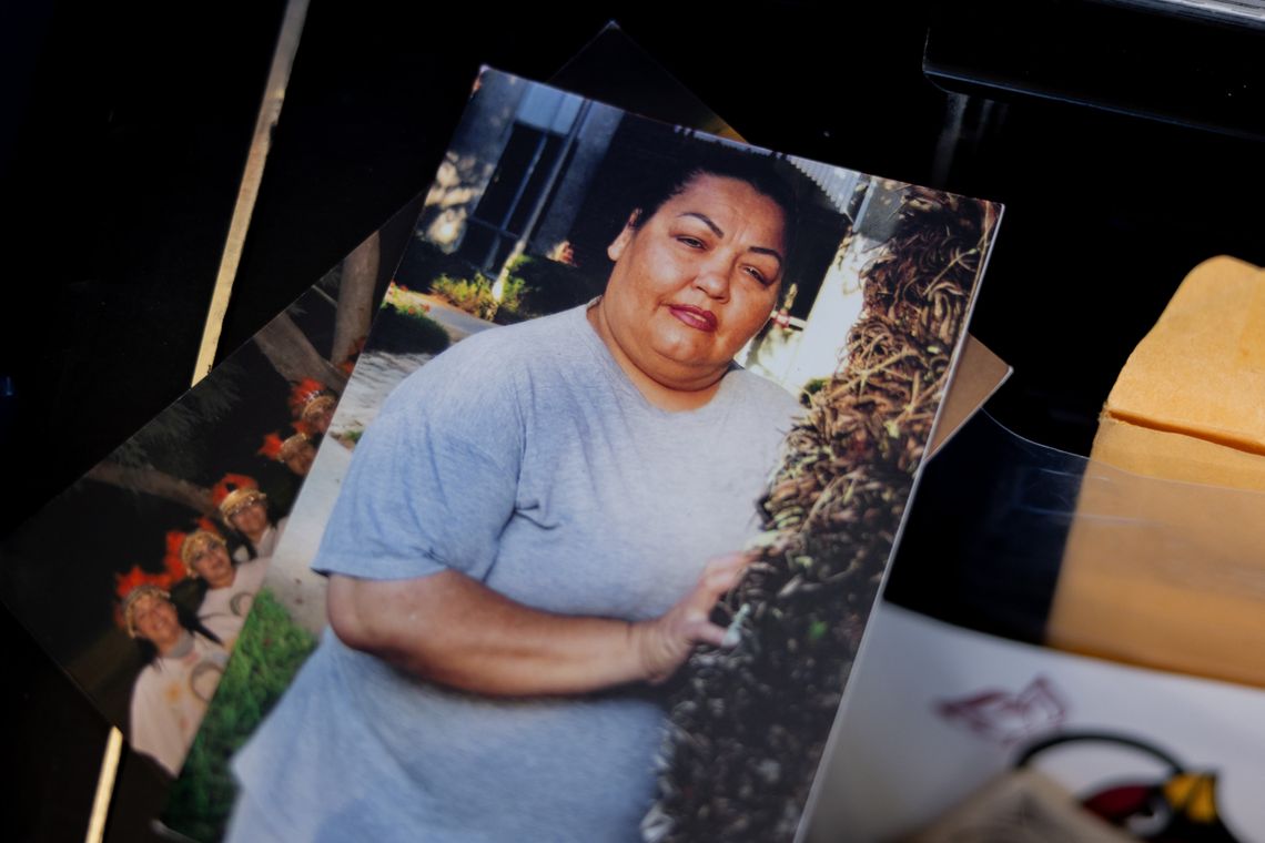 A photo shows a printed photo of a woman in a grey T-shirt and grey shorts. The printed photo is among a small stack of other printed photos.
