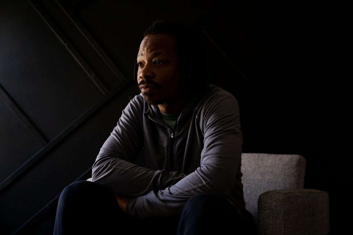 A Black man wearing a gray hoodie looks away from the camera.