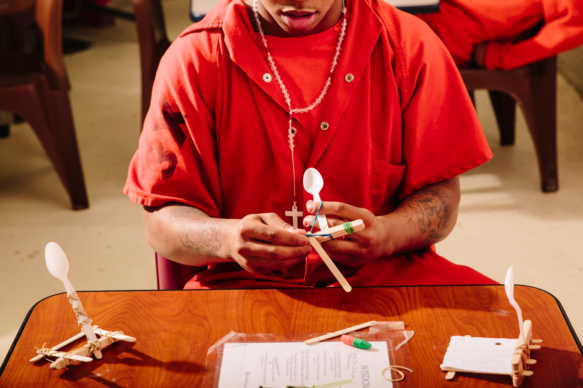 A student constructs a catapult from popsicle sticks, rubber bands, and plastic spoons.