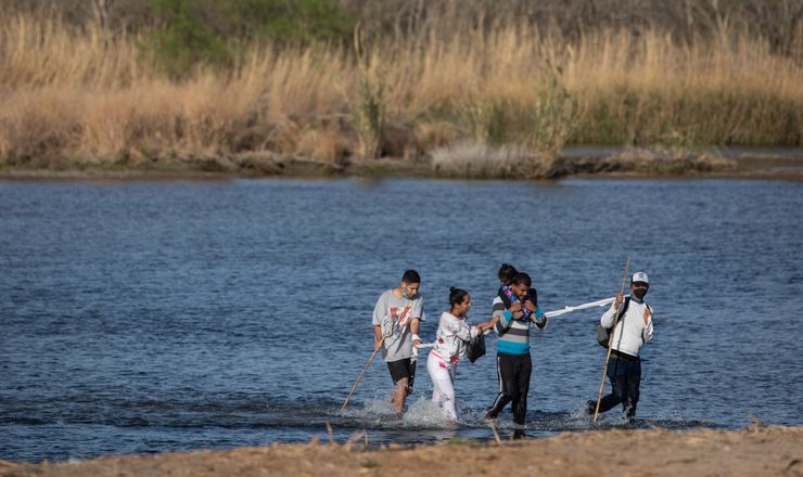 March 2022 - Del Rio, Texas..Migrants from Venezuela cross the Rio Grande into Del Rio on March 23. They were approached by National Guard from North Dakota and told to walk towards the Border Patrol who were gathering migrants under the bridge for transport.