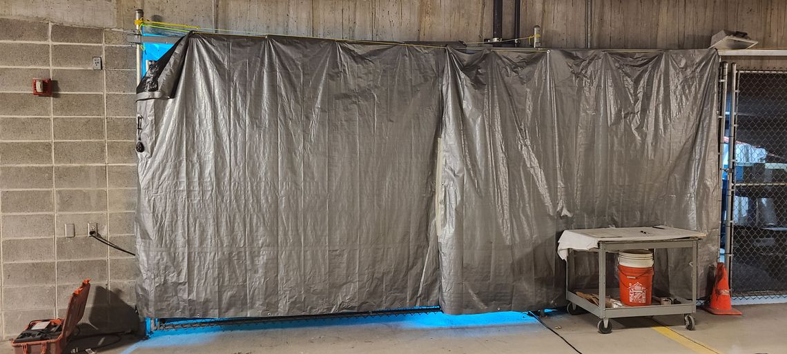 At the Dane County Jail in Madison, Wisconsin, a robot that emits ultraviolet light is behind a tarp, which is used to protect people from exposure to the machine’s powerful rays.