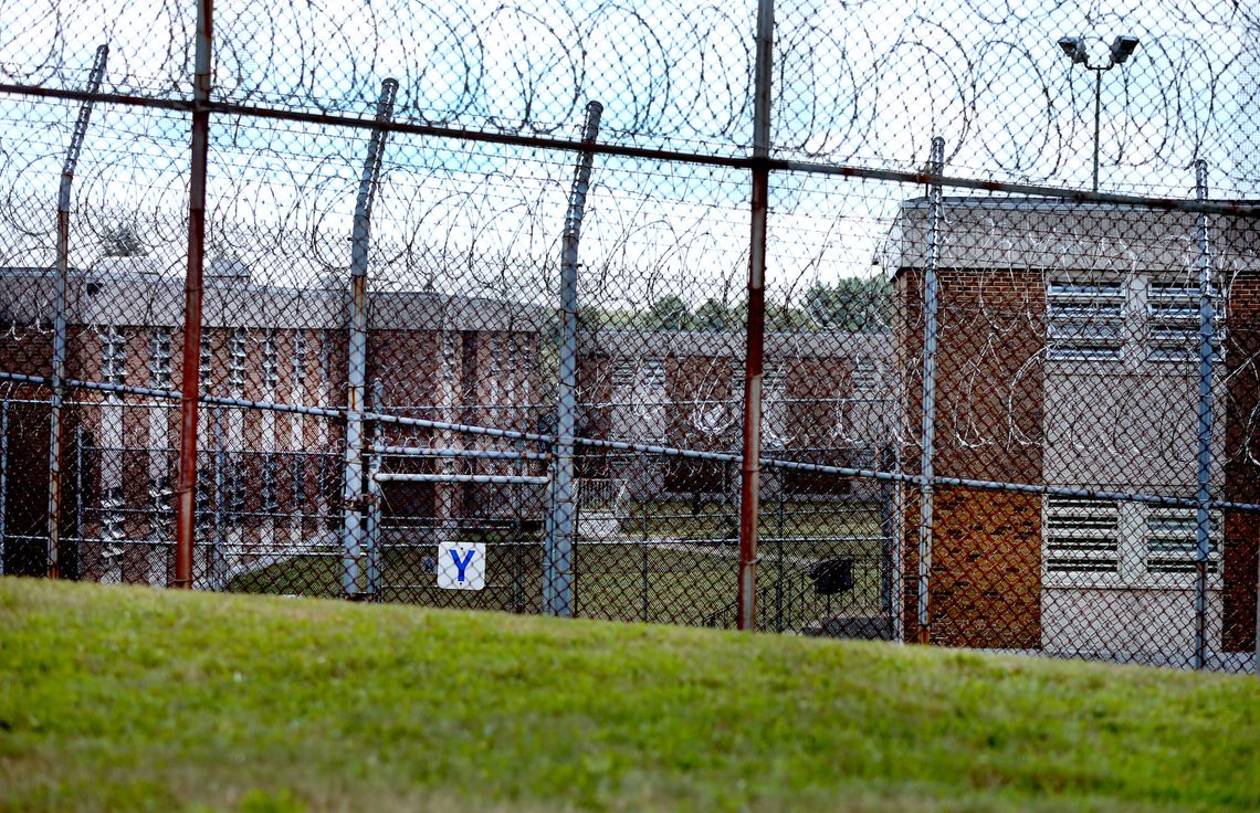 Razor wire surrounds a brick building and courtyard. 