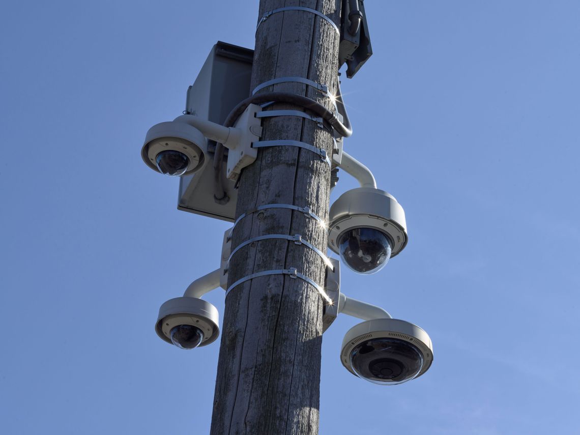 A photograph of four surveillance cameras mounted on a wooden pole. 