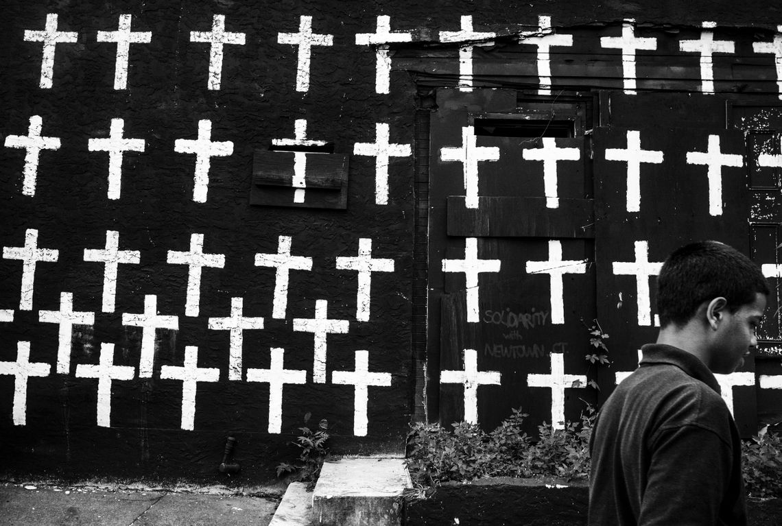 A boy walks by a wall of crosses on Jasper Street in Camden, N.J., on July 17, 2013. There are 67 crosses, each symbolizing a homicide that occurred in 2012. 