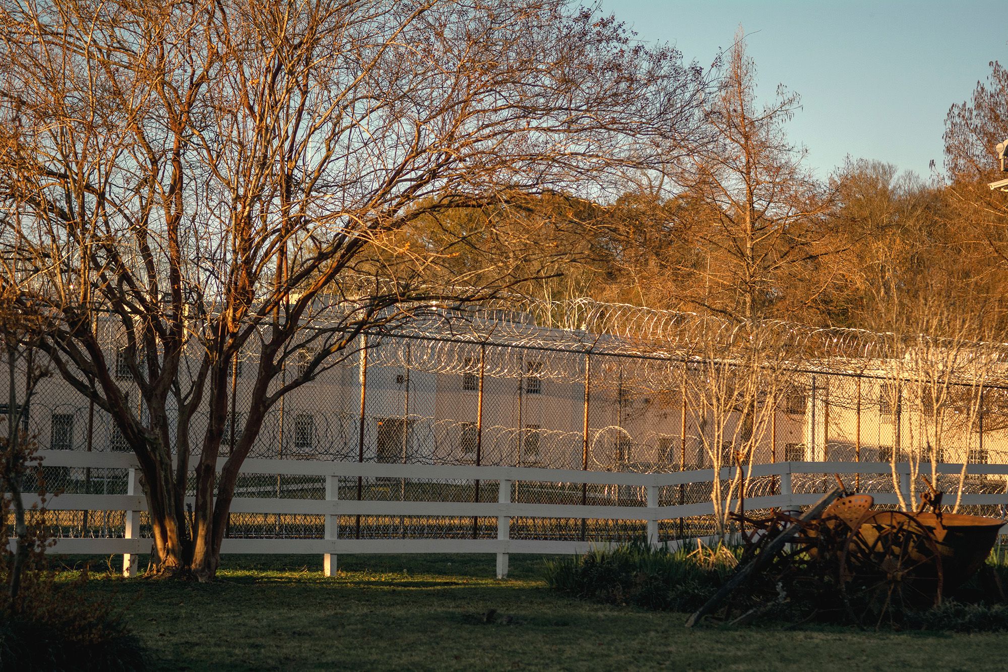 A barbed wire fence surrounds a tan-colored building. 

