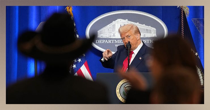 President Trump, a White man wearing a navy blue suit jacket, white button-down shirt and red tie, points at members of the audience. In the foreground of the photo, there are silhouettes of audience members, including one person wearing a cowboy hat. Behind Trump is a cobalt blue backdrop and a sign that says “Department of Justice.” 