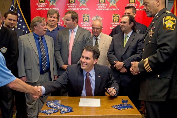 Wisconsin Governor Scott Walker signs a gun bill at the Milwaukee County Sheriff’s office on June. 24.