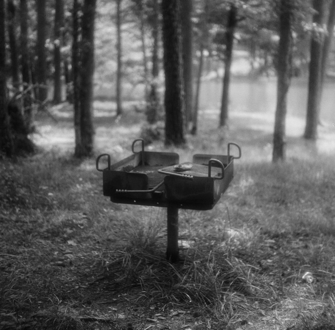 A black-and-white photo of an outdoor grill at a park. 