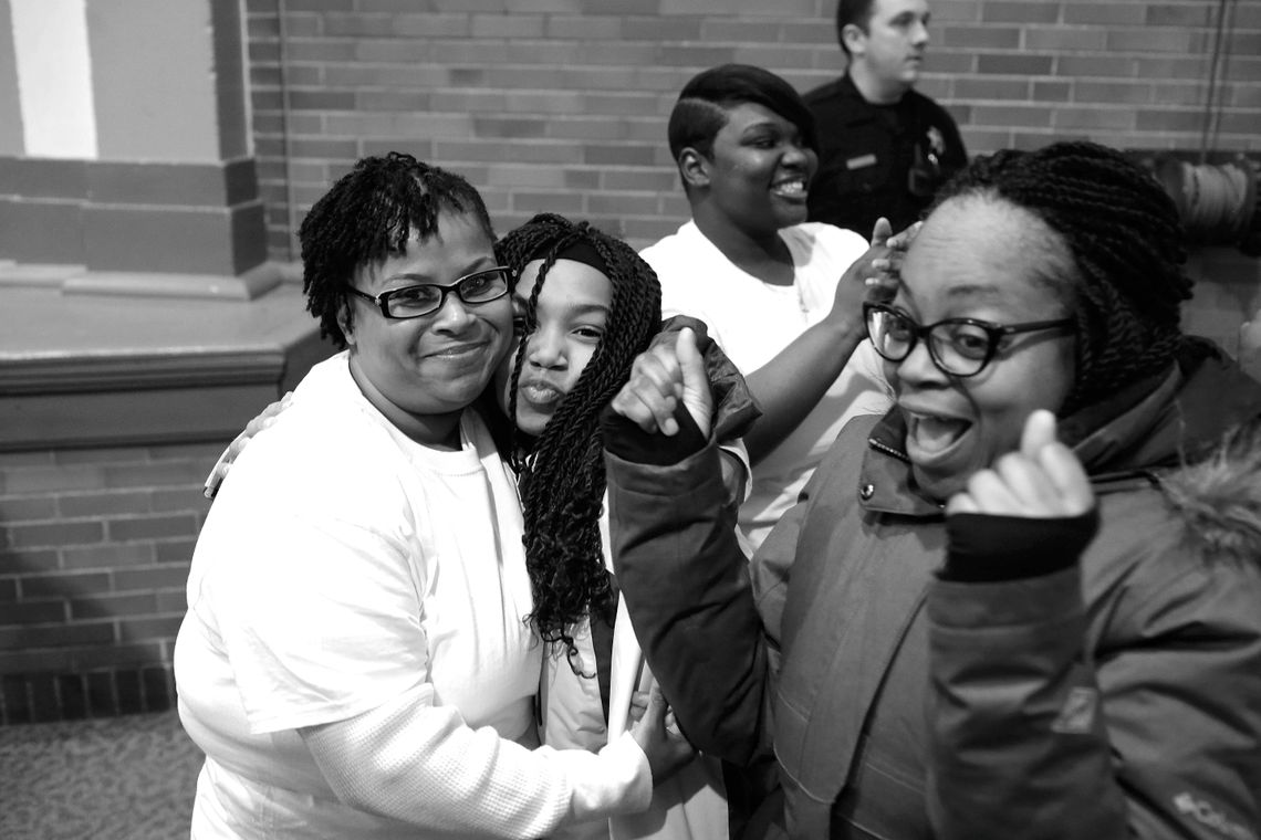 Karena Edwards hugs her daughter, Karon Scott, as families arrive to be reunited with their mothers in prison. In the background, Timesha watches her children walk through the door.