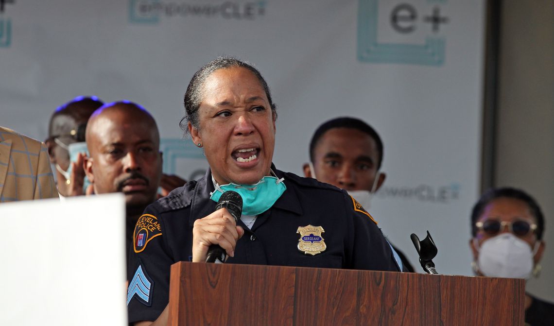 Police Sgt. Charmin Leon, a Black woman wearing a police uniform, speaking at a podium. 